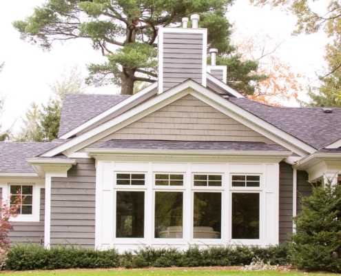 Mississauga home with large windows, wood siding and shingled roof.