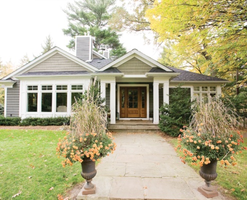 Home renovation with wood front door, stone walkway and white eaves.