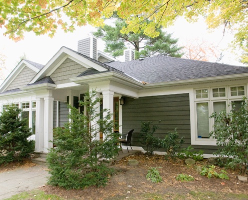 Traditional home with white columns, covered entry and green siding.