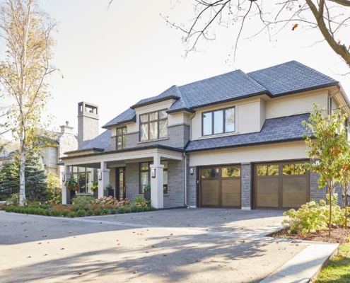 Transitional home with wood garage door, flat roof and covered entry.