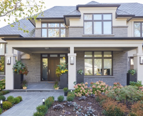 House exterior with stucco siding, horizontal stone and wall sconces.