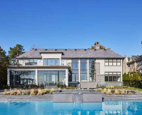 Transitional home with wood garage door, flat roof and covered entry.