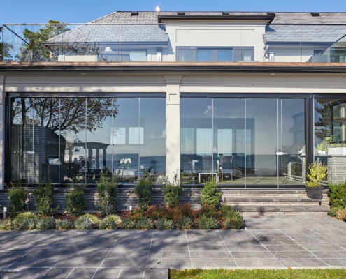 Transitional home with floor to ceiling glass, stucco columns and second floor balcony.