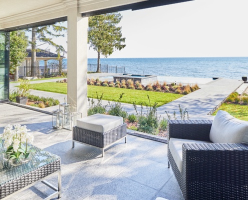 Stone covered patio with stucco columns and lakefront view.