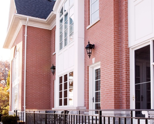 Red brick house with stone siding, white trim and shingled roof.