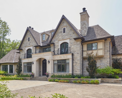 Traditional custom home with stucco siding, arched entry and stone planters.