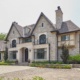 Traditional custom home with stucco siding, arched entry and stone planters.