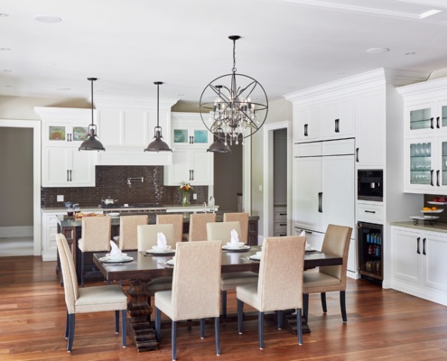 Traditional kitchen with white cabinets, brown backsplash and hardwood floor.