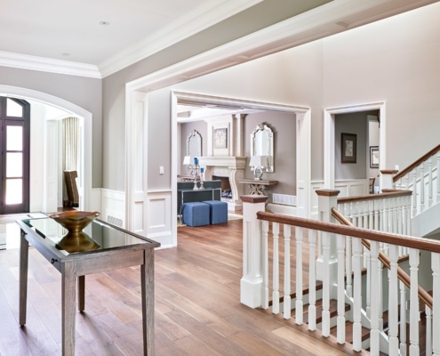 Traditional foyer with arched entry, white wainscoting, and white staircase.