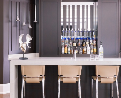 Home bar with white countertop, wood cabinets antertd wood floor.