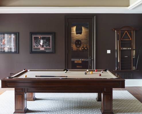 Home games room with white trim, wine cellar and hard wood floors.