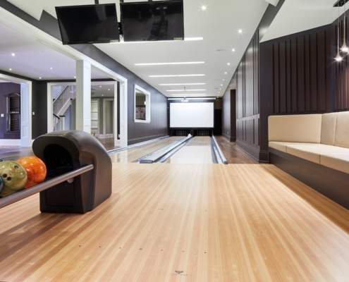 Home bowling alley with wood floor and wood paneling.