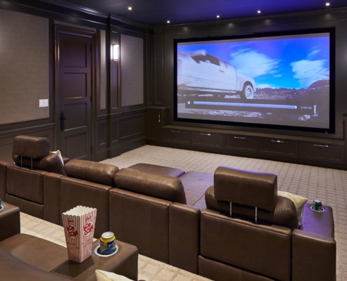 Home theater with wood paneling, brown chairs and carpet.