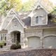 Custom home with stone skirt, arched garage doors and vertical siding.