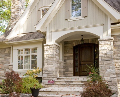 Home front entry with wood front door, stone steps and white trim.