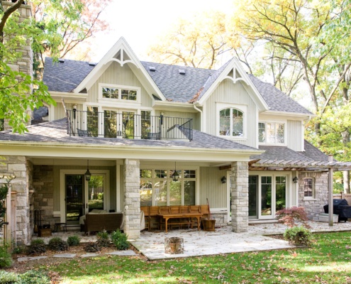 Home rear exterior with wood siding, stone columns and covered porch.