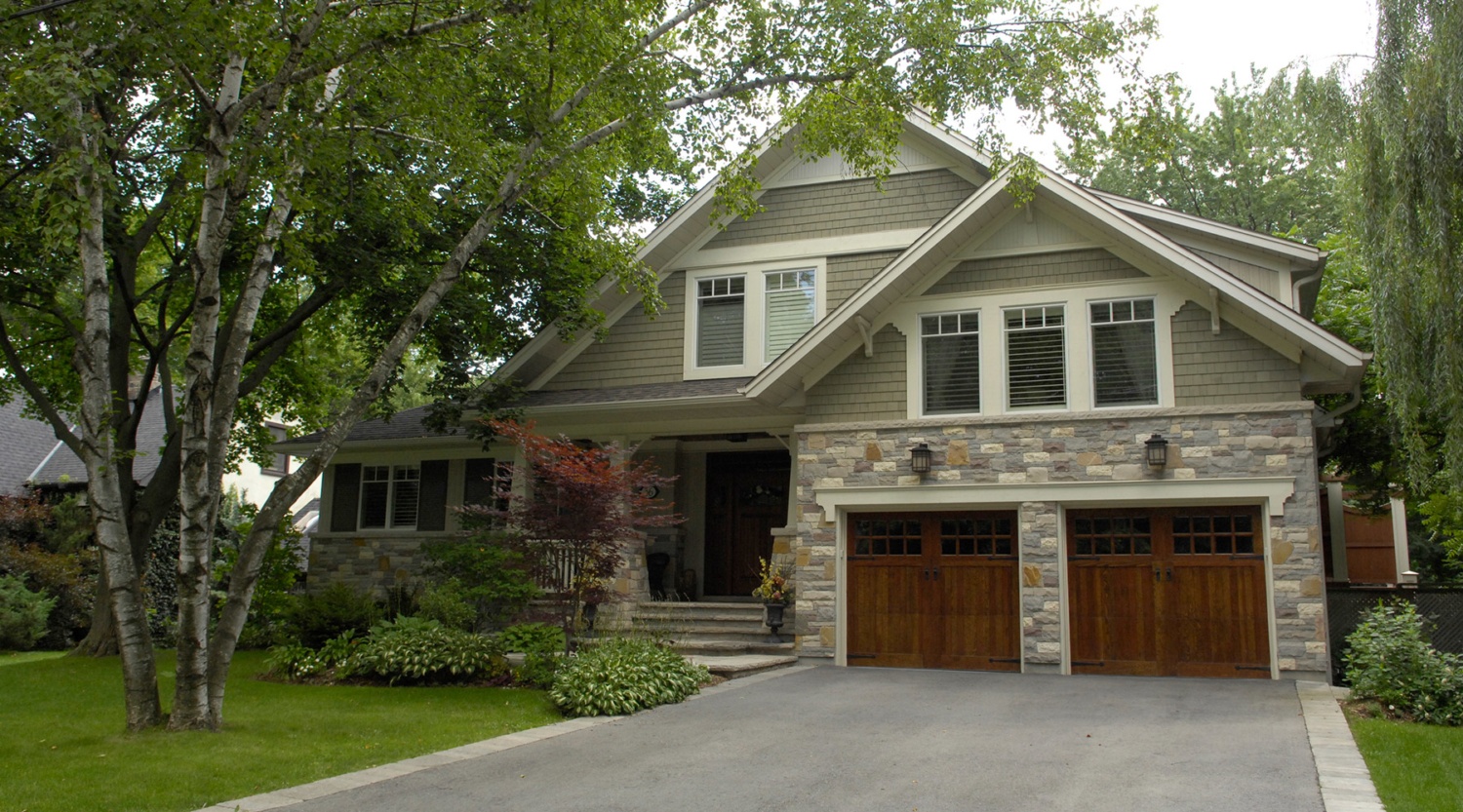 Home renovation with wood garage door, natural stone and white trim.
