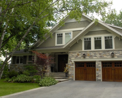 Home renovation with wood garage door, natural stone and white trim.
