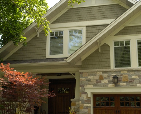 Traditional home with white frame windows, gabled roof and wood siding.