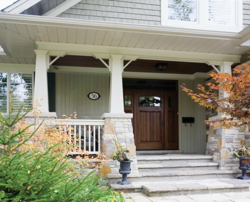 Front facade of house with covered porch, wood front door and wood soffit.