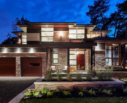 Natural modern home with metal cladding, wood garage door and steel columns.
