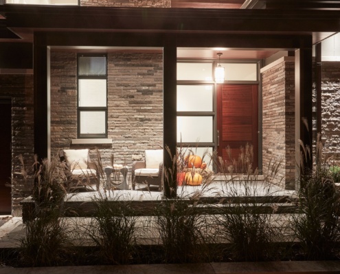 Home covered entry with natural stone, brick and black frame windows.