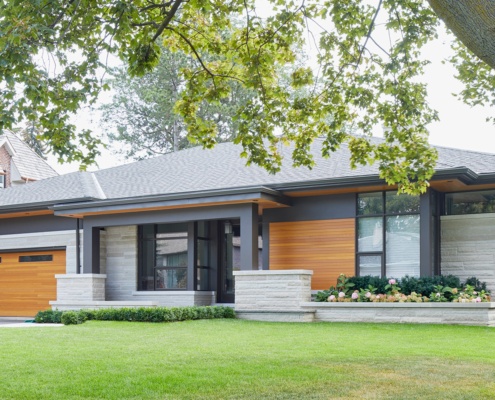 Toronto custom home with wood soffit, black frame window and stone planters.