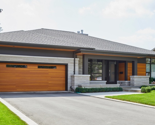 Contemporary bungalow with wood garage door, metal cladding and floating roof.