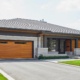 Contemporary bungalow with wood garage door, metal cladding and floating roof.