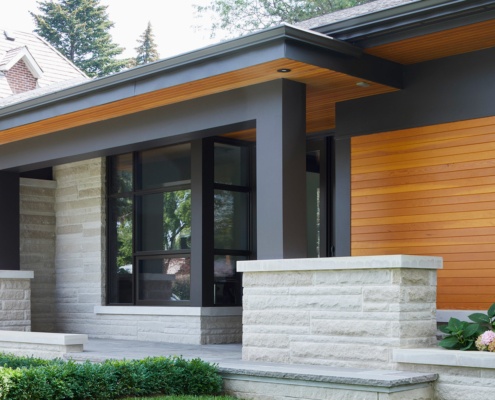 Modern bungalow with natural stone, wood soffit and corner window.