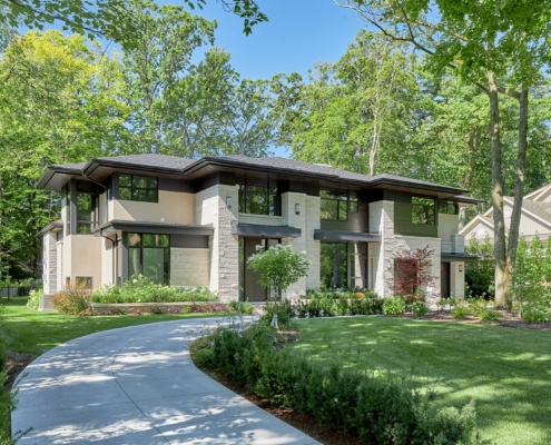 New custom home with stucco siding, dark trim and circular driveway.