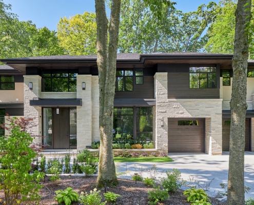 Natural modern house with floor to ceiling window, wood front door and shingled roof.