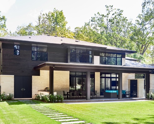 Modern home with wood siding, covered patio and dark trim.