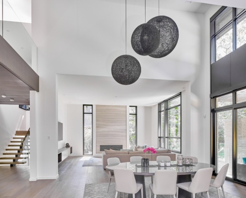 Modern dining room with vaulted ceiling, black frame windows and wood floors.