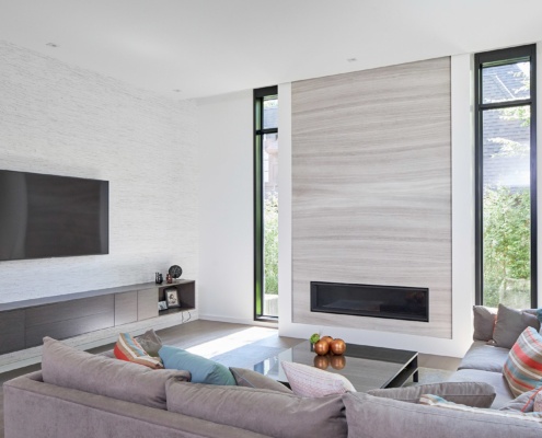 Modern family room with wood fireplace, black frame window and hardwood floor.