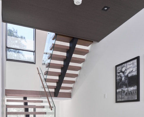 Floating stair with wood treads, glass railing and white walls.