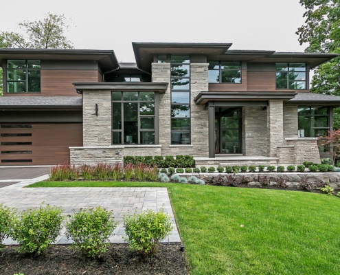 Custom home with floor to ceiling window, wood siding and flat roof.