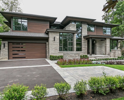 Natural modern home with wood garage door, angled wall and sconce lighting.