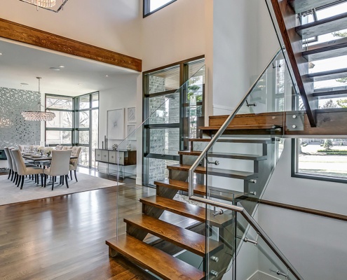 Floating stair with wood treads, glass railing and black frame window.