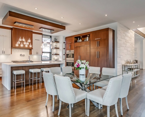 Contemporary dining room with glass dining table, hardwood floor and white chairs.