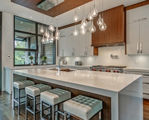 Modern kitchen with white island, white cabinet and pendant lighting.