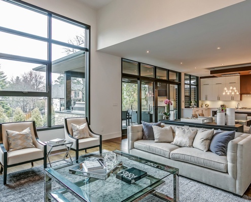 Modern family room with black frame windows, gray carpet and white trim.