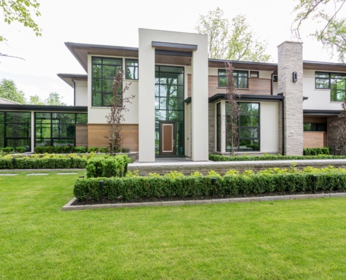 Modern house with dark trim, two storey entry and stone landscape wall.