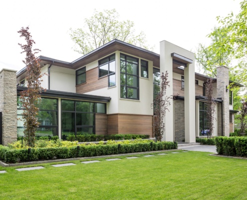 Custom home with dark wood, black frame windows and beige siding.