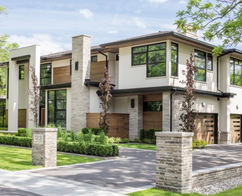 Contemporary house with stone columns, stucco siding and corner windows.