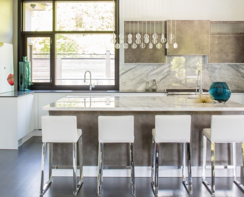 Modern kitchen with white island, marble backsplash and black frame window.
