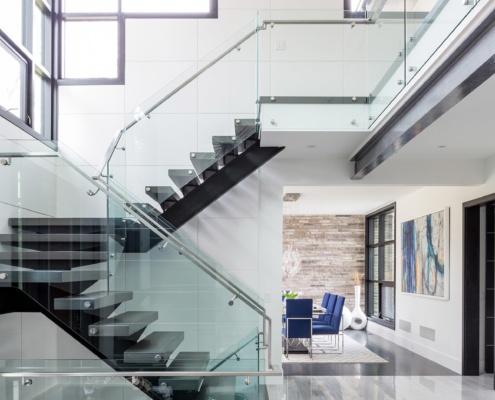 Modern home interior with floating staircase, steel beam and tile wall.