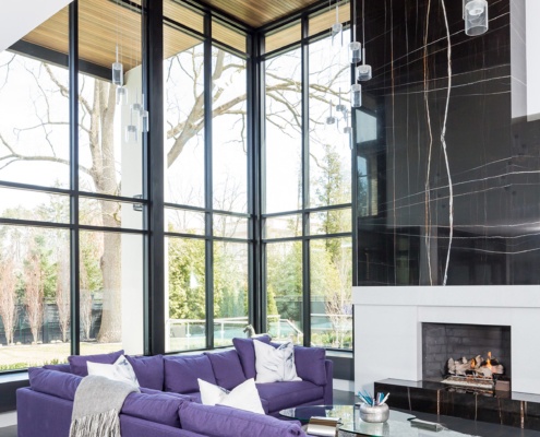 Living room with stone fireplace, marble wall and floor to ceiling windows.