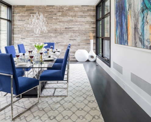 Dining room with stone wall, floor to ceiling window and white baseboard.