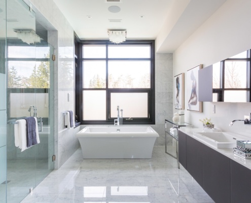 Large bathroom with tile wall, glass shower and corner window.